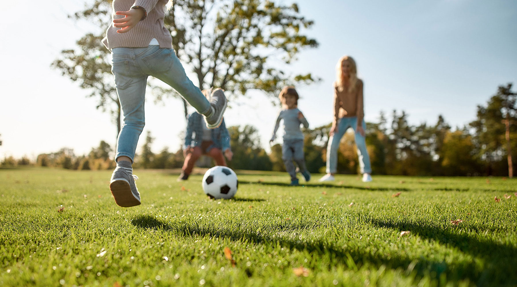 Familie spielt auf einem schönen Rasen Fußball im Garten.